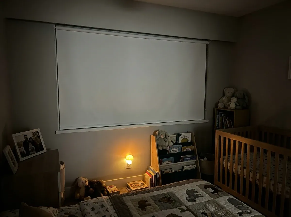 Blackout roller shades fully lowered in a darkened Burnaby high-rise bedroom